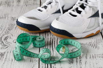 Fototapeta na wymiar Sport shoes and measure tape on white background.Sport shoes and centimeter as a fitness running