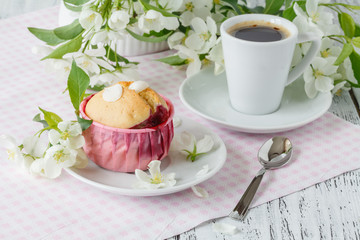 spring Breakfast. muffin and cup of tea on a table, the branch blossoming in the small white flowers