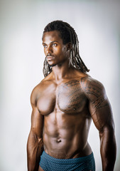 African American bodybuilder man, naked muscular torso, wearing pants only, against white...