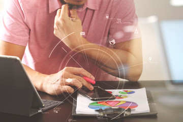 businessman in pink t-shirt working with smart phone and digitl tablet computer and document on wooden desk in modern office with virtual icon diagram