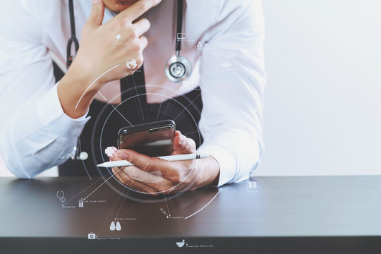 Close Up Of Smart Medical Doctor Working With Smart Phone And Stethoscope On Dark Wooden Desk With Virtual Icon Diagram