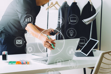 Fashion designer working with mobile phone and using laptop with digital tablet computer in modern studio