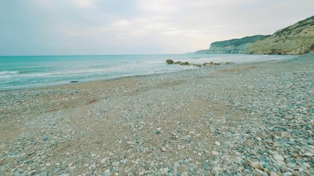 POV Way of someone to the magnificent beautiful sea. Walk along the waterfront. Walking along the pebble beach to the seashore, in the background mountains and clear sky