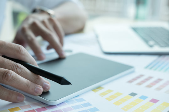 young graphic designer working with computer, color swatch. creative man using tablet at office.  Architect with sample colour catalog. business, technology