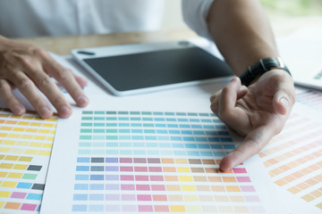 young graphic designer working with computer, color swatch. creative man using digital tablet at modern office.  Architect with work tools and sample colour catalog. business, technology,