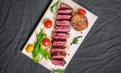 New york strip porterhouse steak meat with vegetables against black background