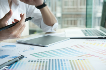Fototapeta premium young graphic designer working with computer and color swatch. creative man using stylus pen and digital tablet at modern office. Architect using work tools and sample colour catalog. 