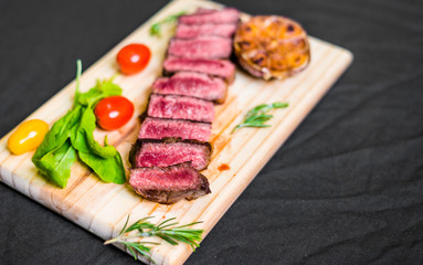 New york strip porterhouse steak meat with vegetables against black background