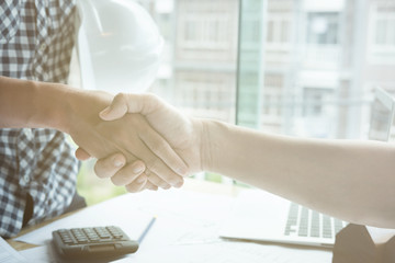 Architect and customer shaking hands at workplace. Engineer handshaking with partner for successful deal in building project development. business teamwork, cooperation, success collaboration concept