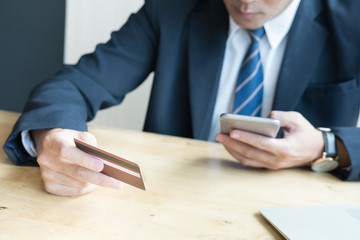 male holding a credit card and using laptop computer for online shopping. businessman purchase goods from internet. man make payment on bank website