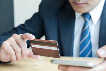 male holding a credit card and using smart mobile phone for online shopping. businessman purchase goods from internet. man make payment on bank website