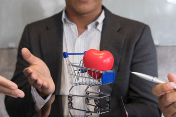 businessman showing red heart in a blue shopping cart on digital tablet. Valentine's Day, buying love concept