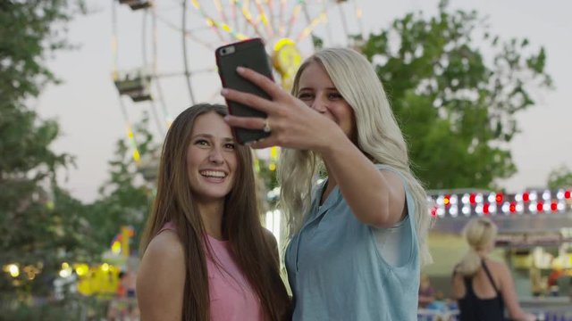 Medium shot of women taking cell phone selfie at amusement park. Pleasant Grove, Utah, United States