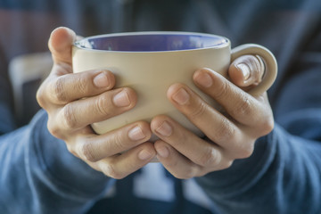 Female hands holding cups of coffee, front view.