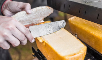 Chef at a street market preparing sandwich with smoked salmon and raclette grilled melted cheese