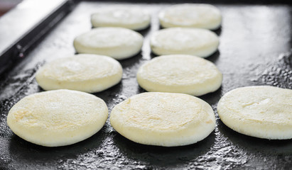 Close up photo of raw uncooked arepas, traditional Colombian corn patties filled with cheese, at a street food market