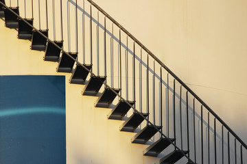 Metal staircase on the oil tank lit by the evening sun.