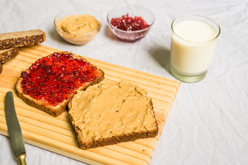 Peanut butter and jelly sandwich on a wooden board against white background