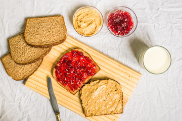 Peanut butter and jelly sandwich on a wooden board against white background