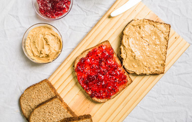 Peanut butter and jelly sandwich on a wooden board against white background