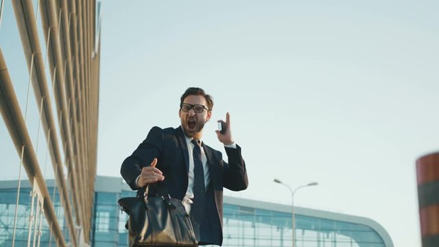 Businessman doing crazy, funny moves while standing outdoors near office building. Business man dancing, doing ninja hands moves. close up