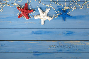 patriotic red white and blue starfish in nautical netting on rustic wood