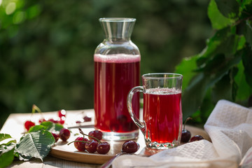 Homemade sour cherry compote in glass cup with jar on bamboo tray