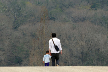 手をつないで歩く父と息子の後ろ姿