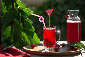 Homemade sour cherry compote in glass cup with jar on bamboo tray