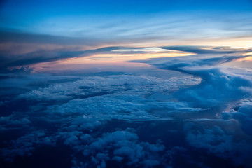 Naklejka na ściany i meble Aerial view of a cloudy sunset while flying above the clouds