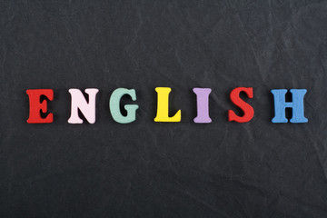 Obraz premium English word on black board background composed from colorful abc alphabet block wooden letters, copy space for ad text. Learning english concept.
