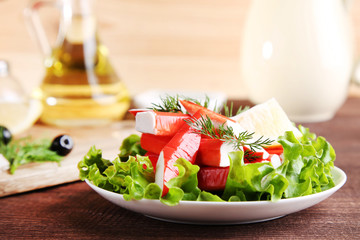 Crab sticks and lettuce in plate on brown wooden table