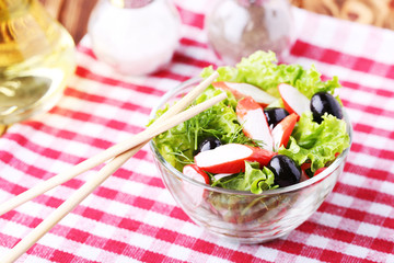Salad with crab sticks, olives and lettuce in a bowl