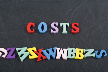 costs word on black board background composed from colorful abc alphabet block wooden letters, copy space for ad text. Learning english concept.