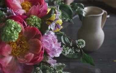 Beautiful bouquet of flowers and pitcher on wooden background