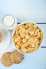 Cornflakes, bottle of milk and cookies on wooden table