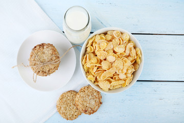 Cornflakes, bottle of milk and cookies on wooden table