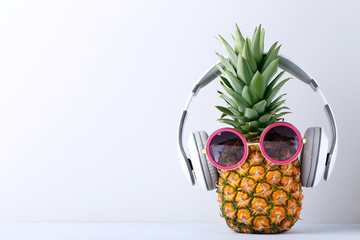 Ripe pineapple with headphones on grey background