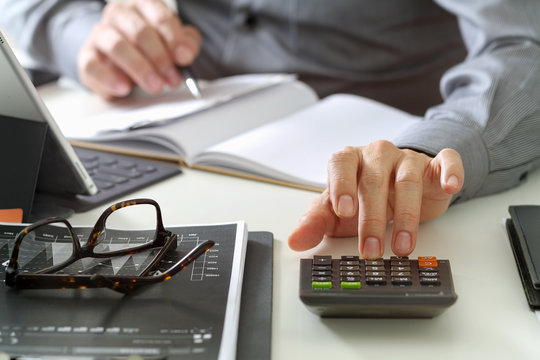 businessman hand working with finances about cost and calculator and latop with mobile phone on withe desk in modern office