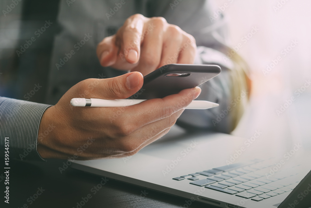 Poster close up of businessman working with mobile phone and stylus pen and laptop computer on wooden desk 