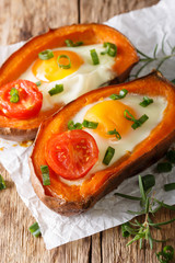 hearty breakfast: sweet potato stuffed with egg and tomato close-up. vertical