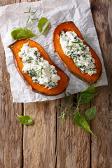 Baked sweet potato stuffed with spinach and cream cheese close-up on the table. vertical top view