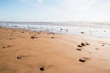 Coast, waves and beach with yellow sand and pebbles