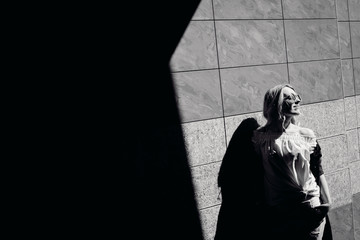 Black and white picture of stunning blonde in sunglasses posing before the wall