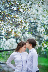 Fototapeta premium The man gently kisses his wife on the forehead for a walk through the flowering magnolia garden