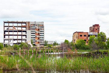 The abandoned building is located among the trees. There is a pond in front of the building. This...