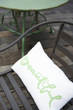 Wooden terrace with wrought-iron chair and table in black and green and beautiful cushion