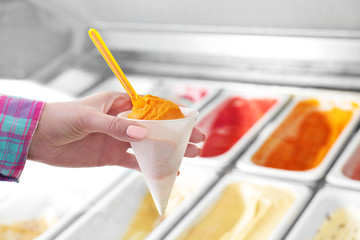 Woman holding portion of ice cream on blurred background