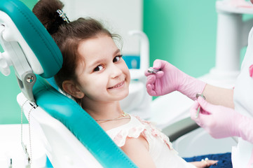 A little girl at a reception with a dentist, sits on a chair