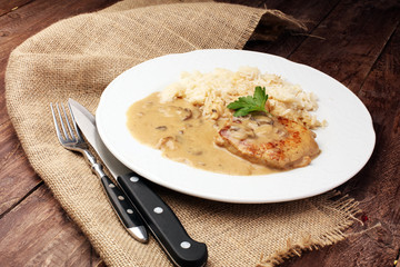 Delicious rice with chicken and vegetables on plate on wooden table